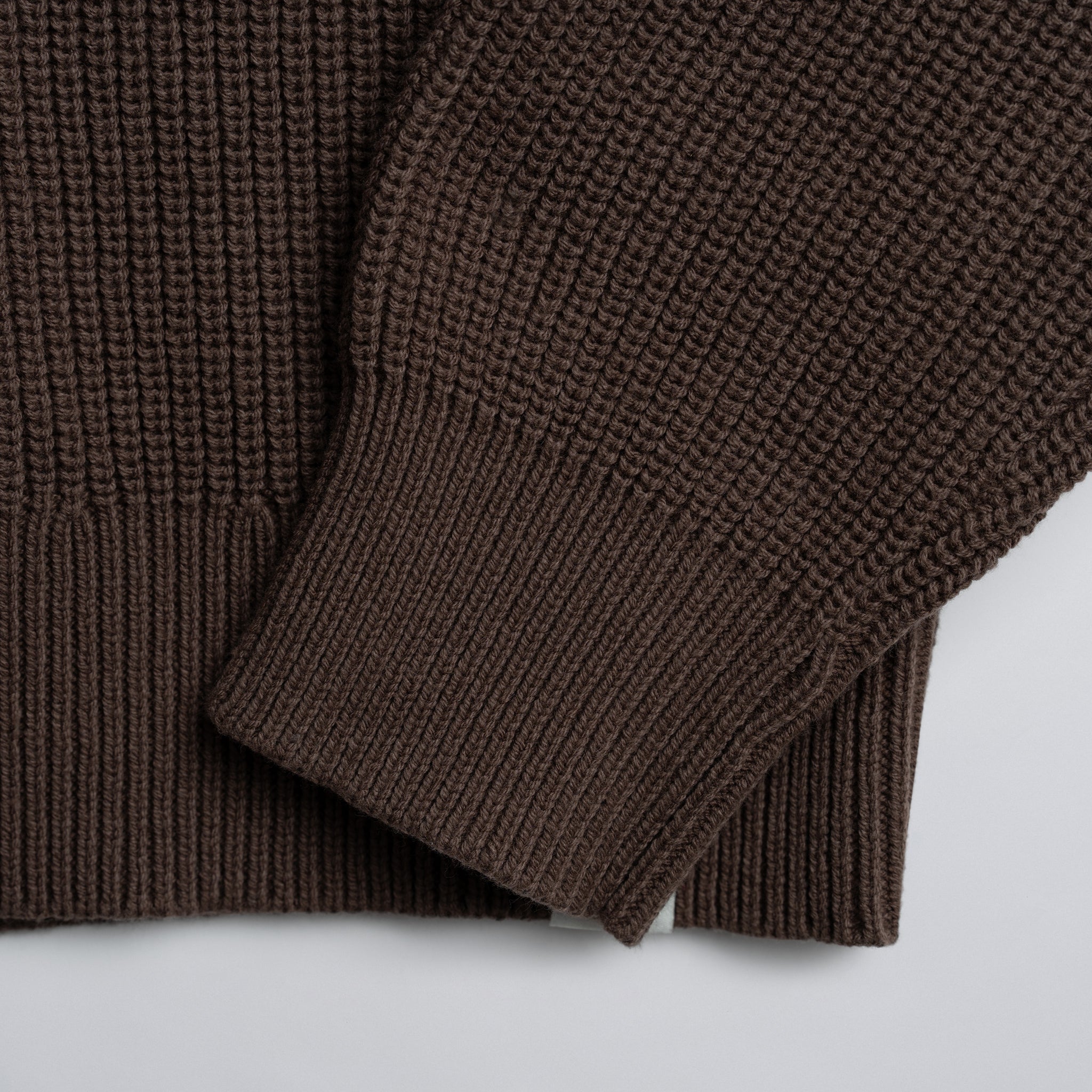Close-up of a brown knitted garment on a light background.