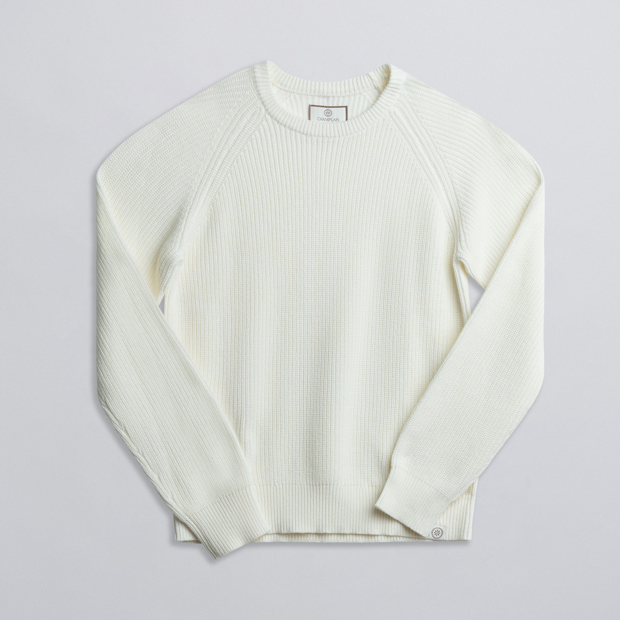A long-sleeved cream-colored fisherman sweater displayed against a neutral background.
