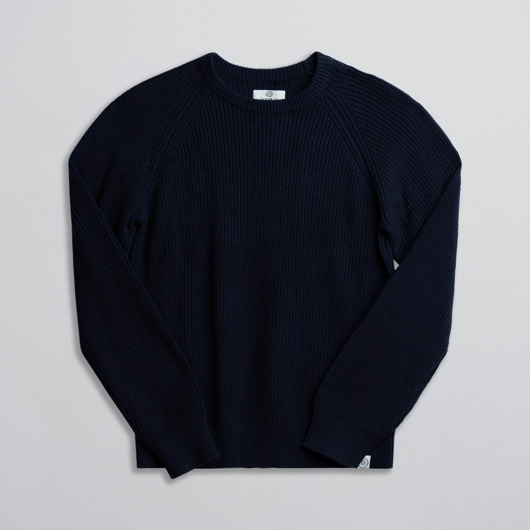 A navy-colored fisherman sweater displayed against a neutral background.