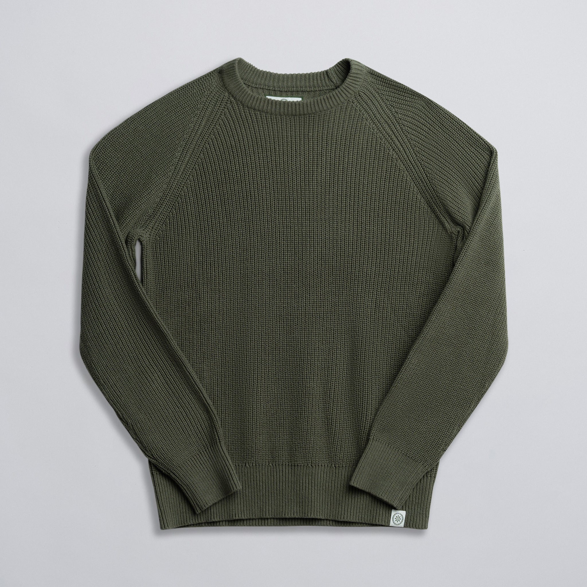 An olive green fisherman sweater laid out flat on a solid background.