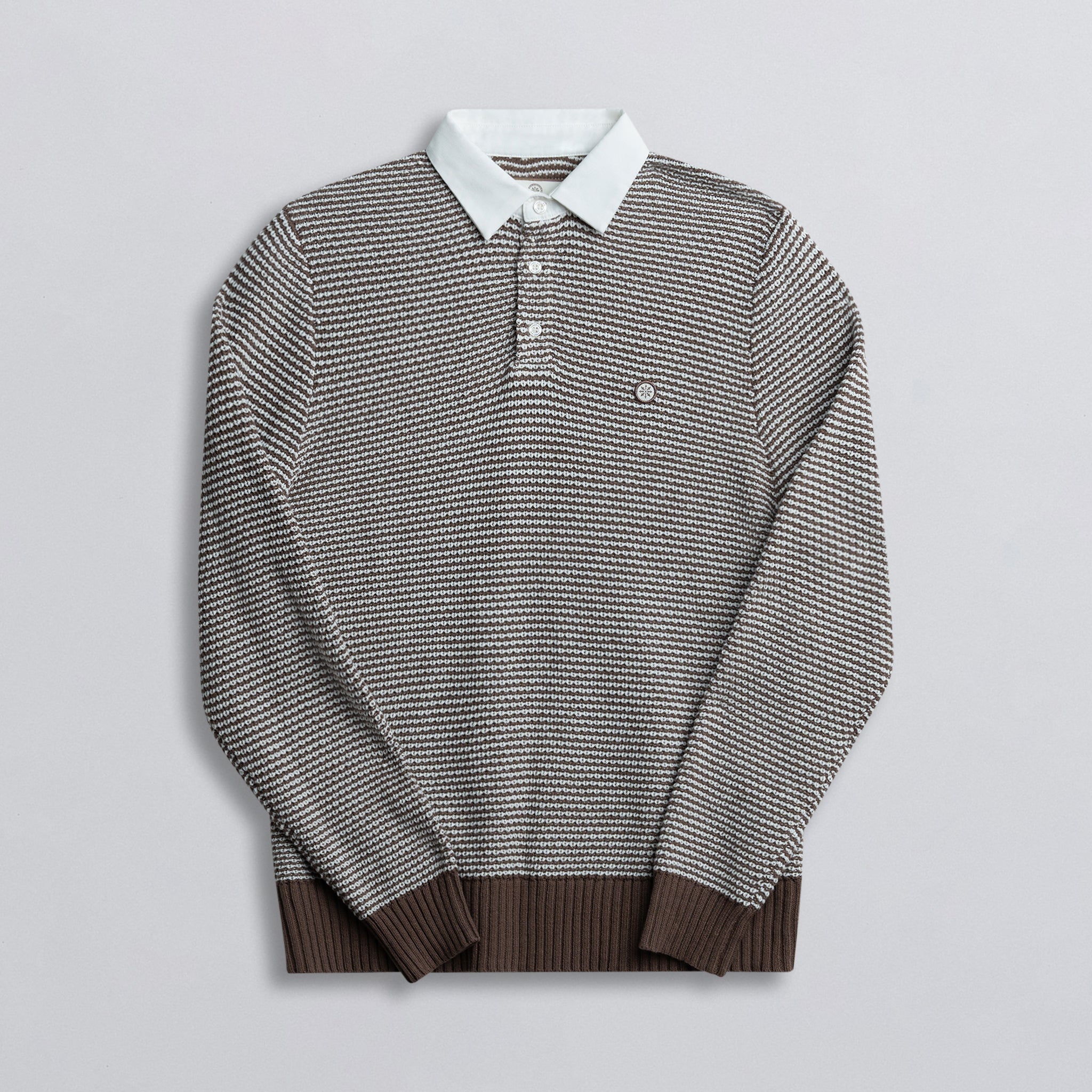 A long-sleeved rugby shirt with a striped pattern, featuring a collar and button-up design, predominantly in brown color with white and darker brown stripes.