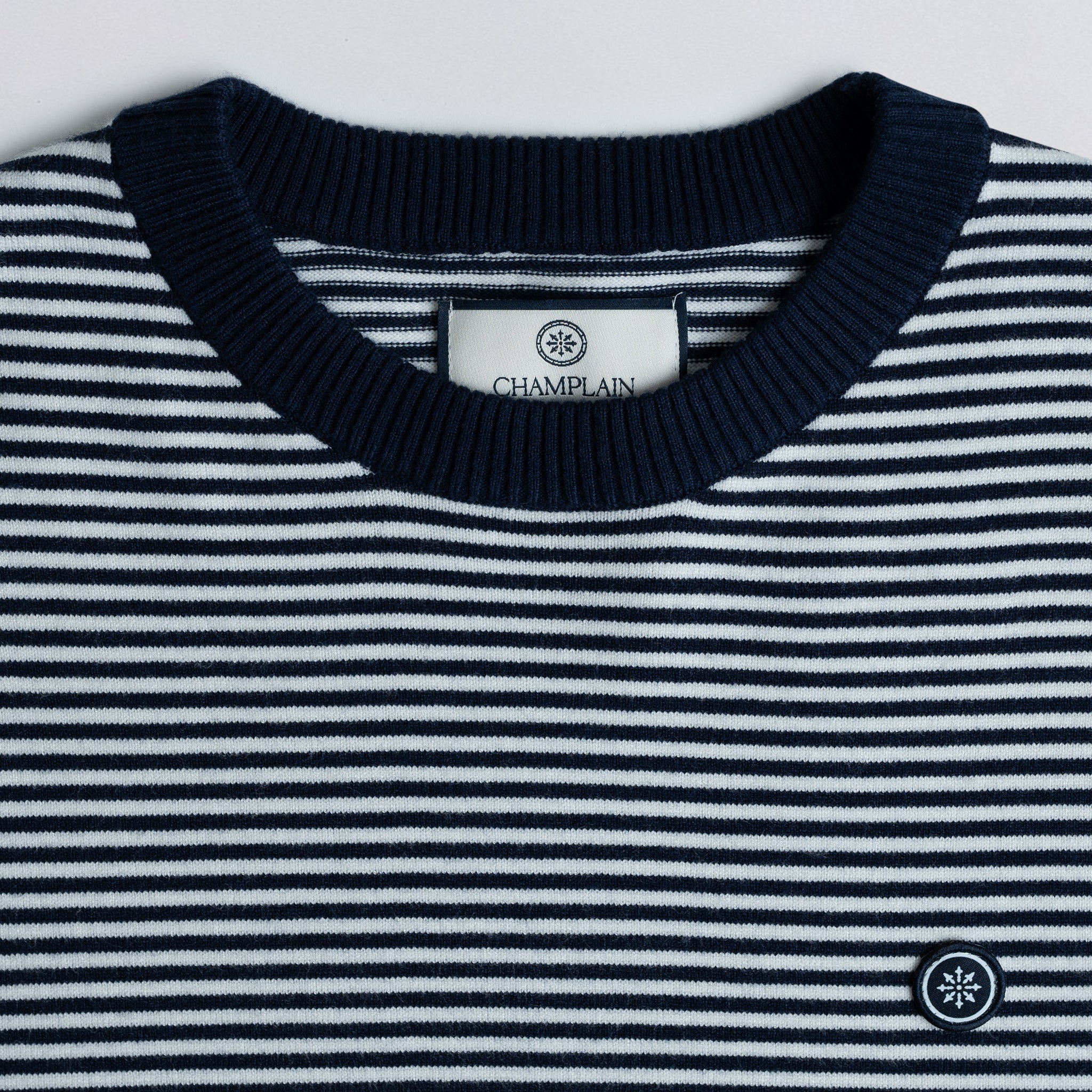Close-up of a striped sweater with a Champlain label on a light gray background