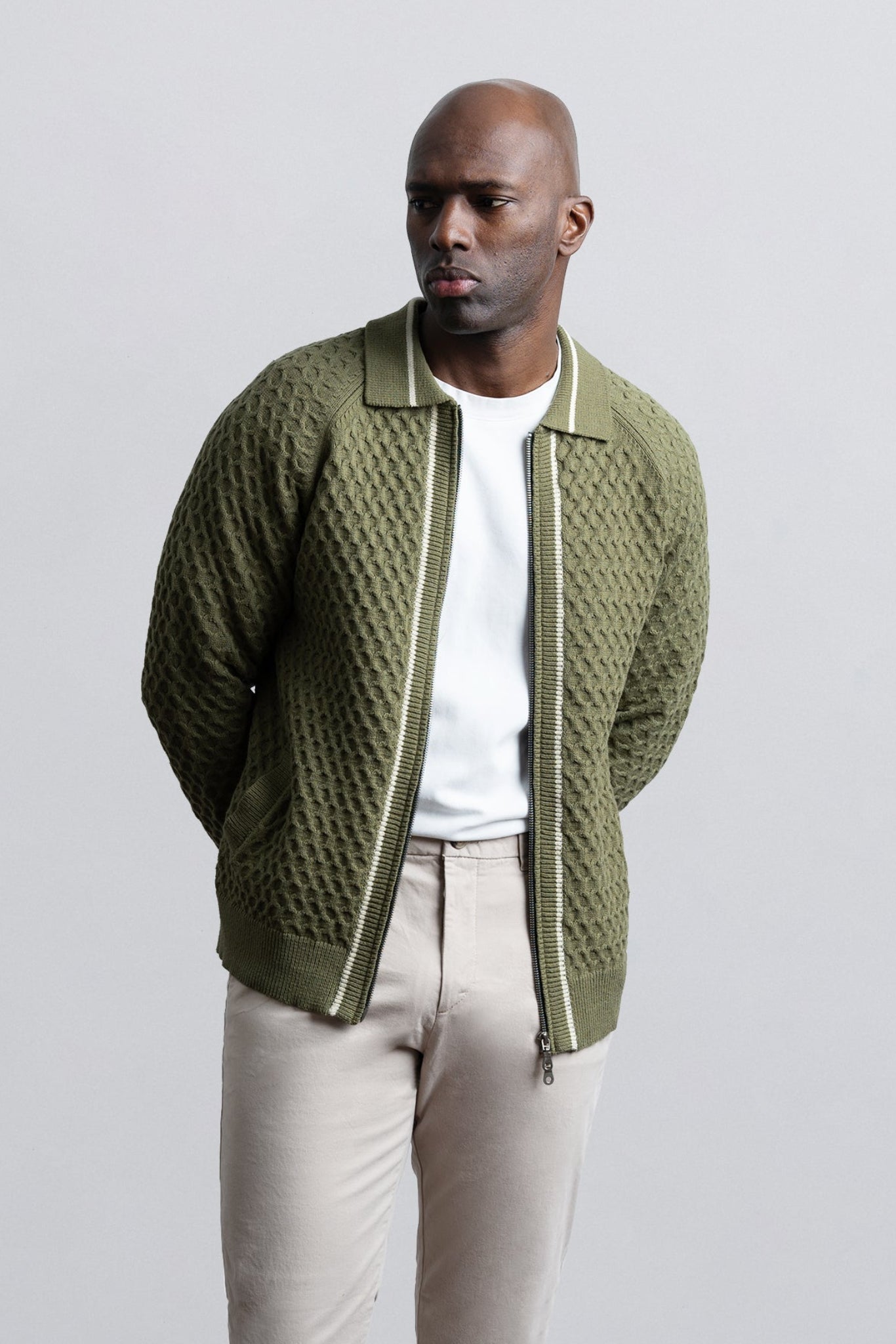 Man wearing a green quilted jacket on a light gray background