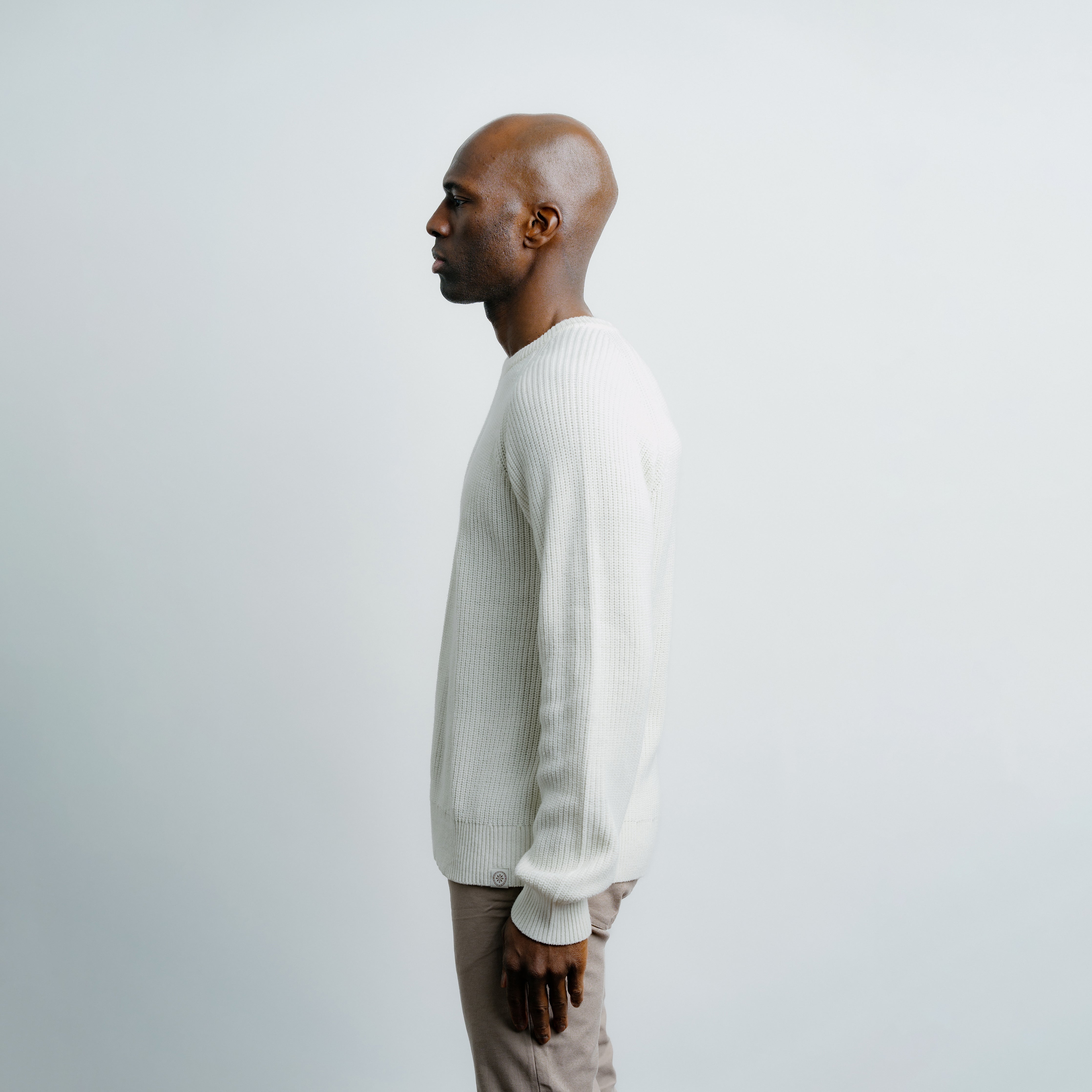 Man wearing a white sweater against a plain background