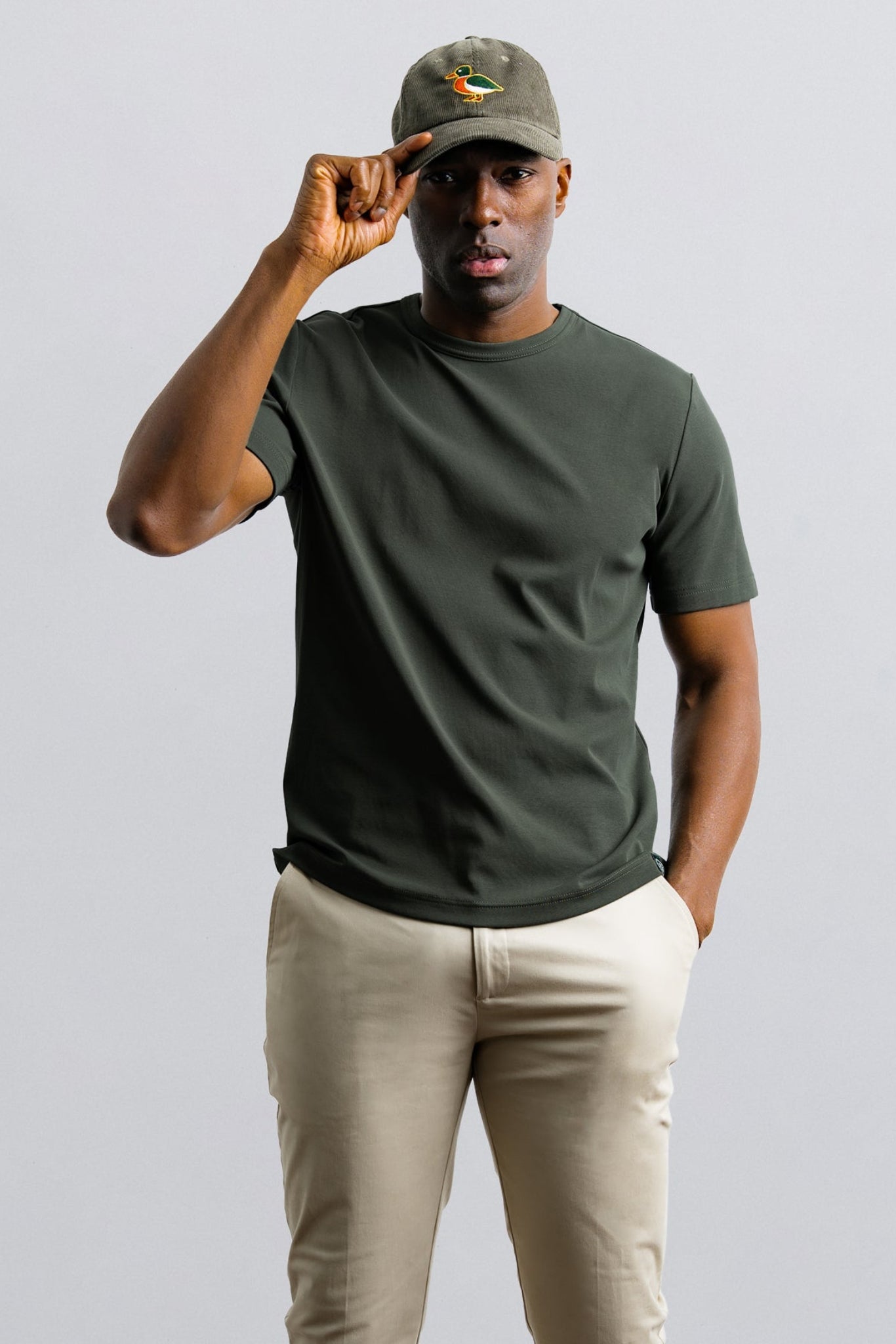 Man wearing a green t-shirt and cap against a plain background
