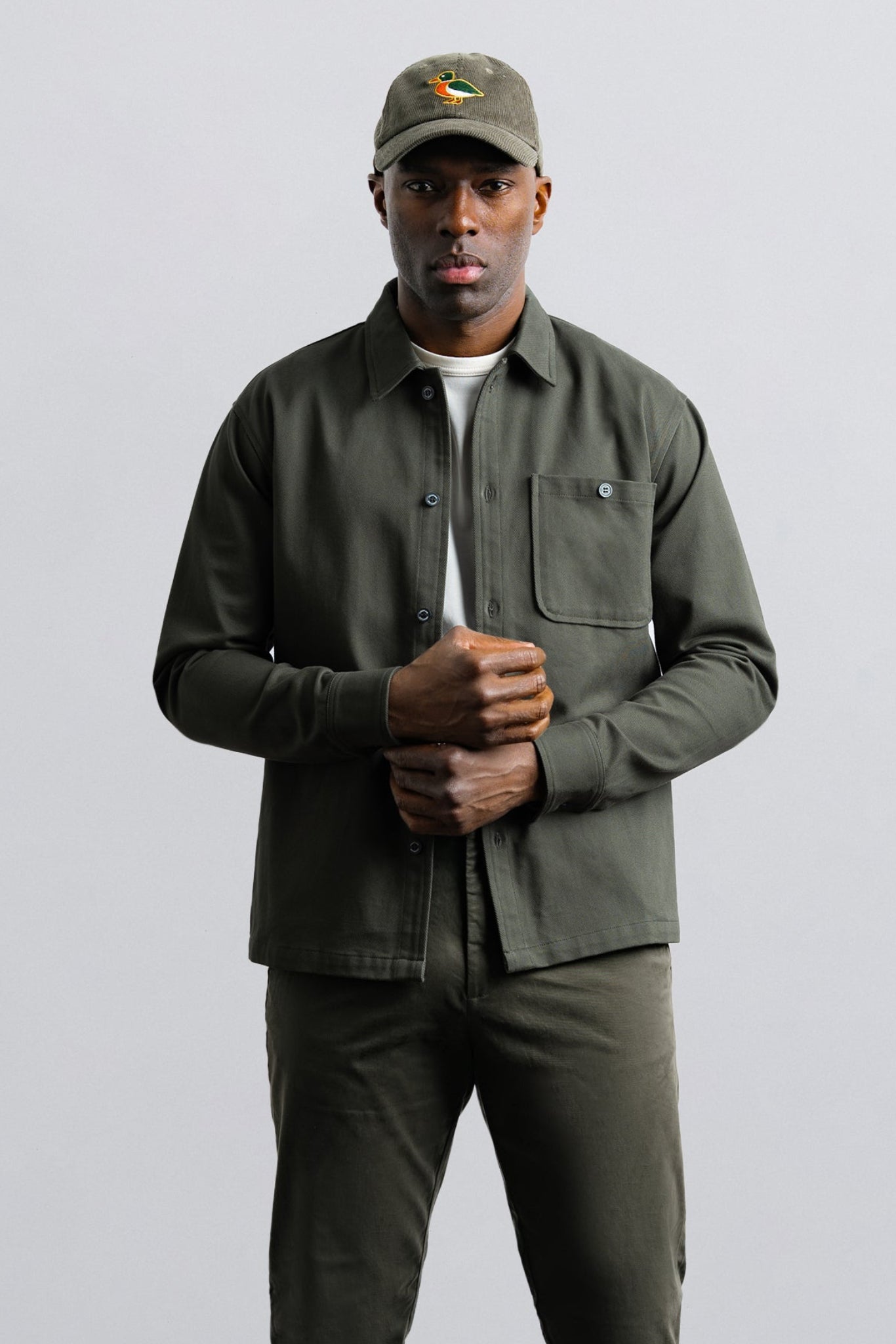 Man wearing a green jacket and cap on a gray background
