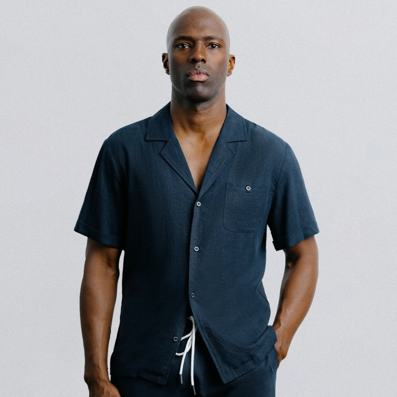 Man wearing a navy blue shirt and shorts set on a light gray background