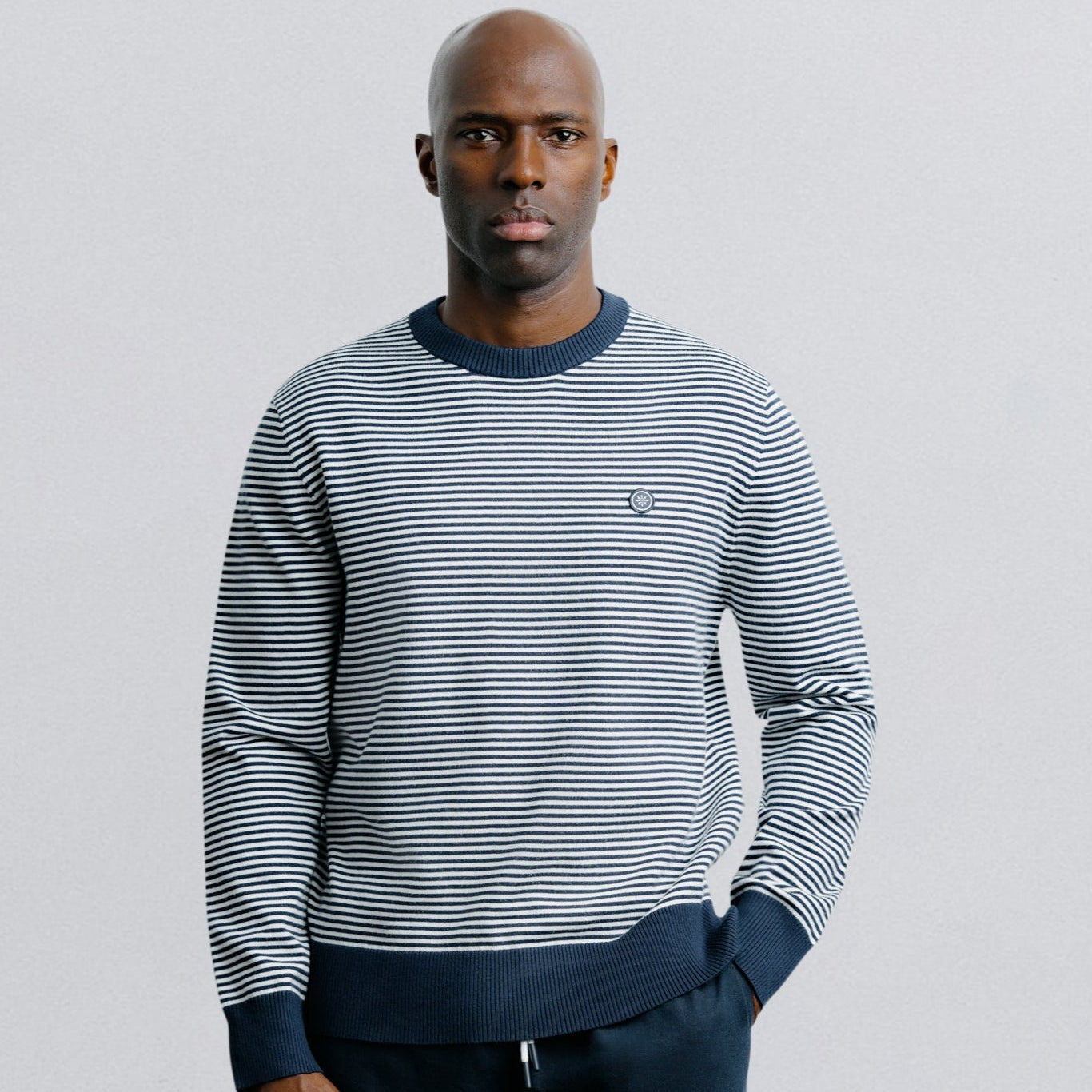 Man wearing a striped sweater and shorts on a plain background