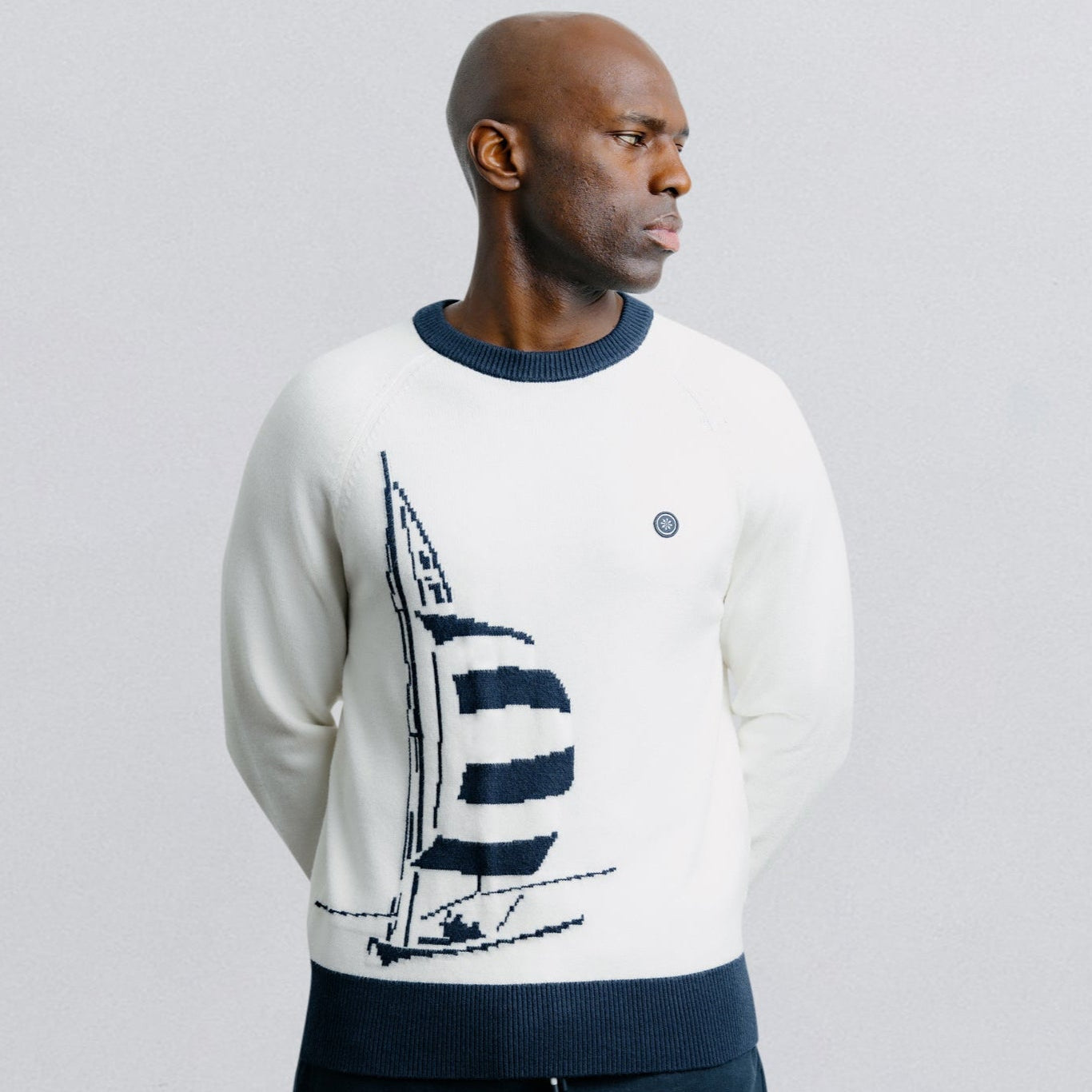Man wearing a sweater with a sailboat design on a plain background