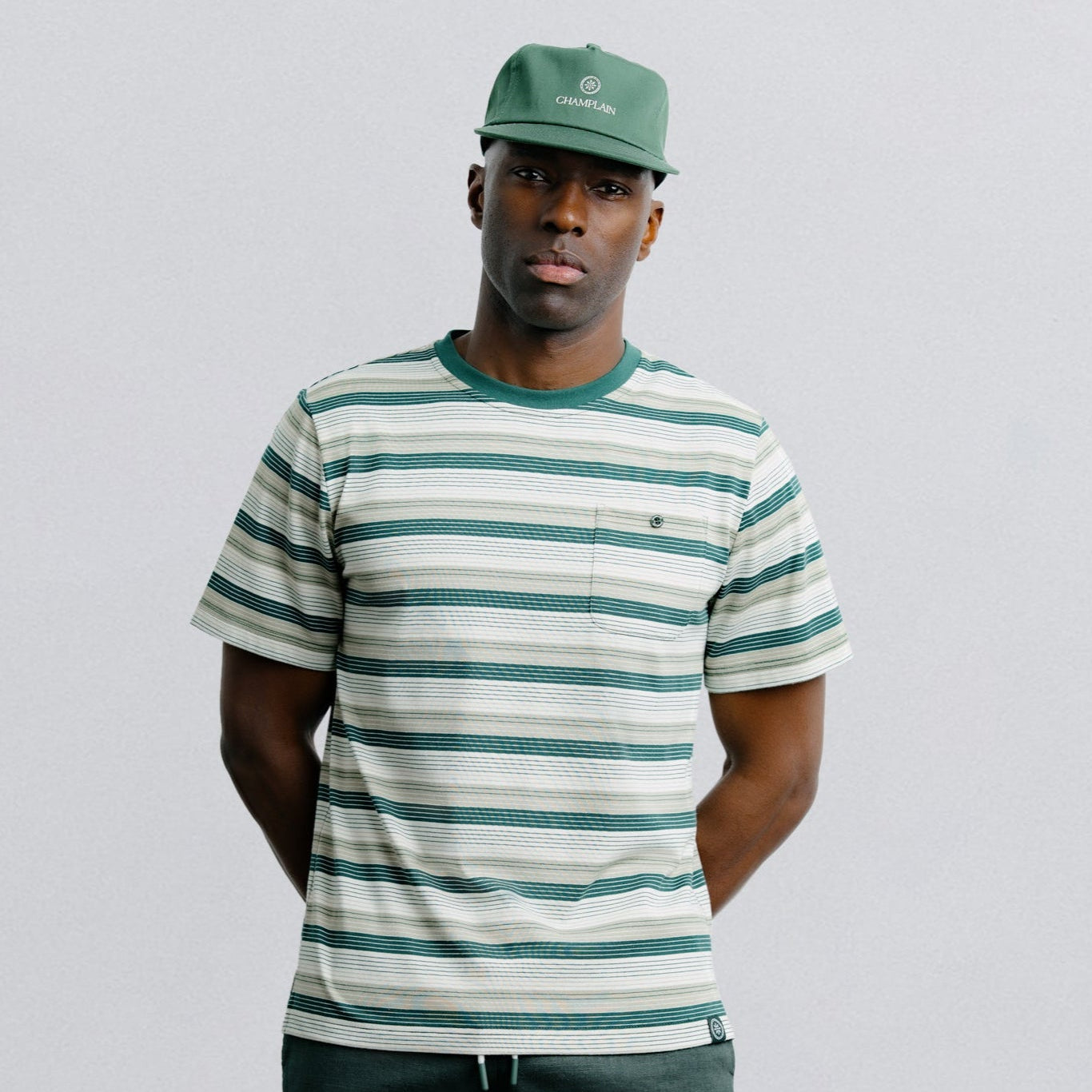 Person wearing a striped shirt and green cap against a plain background