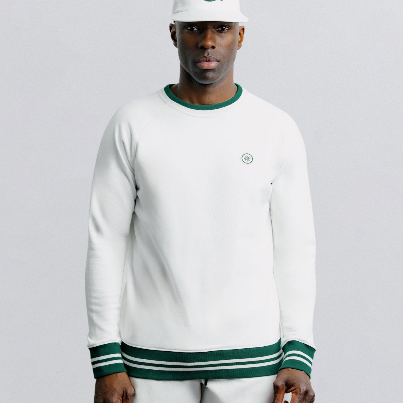 Person wearing a white long-sleeve shirt and shorts with green accents on a gray background