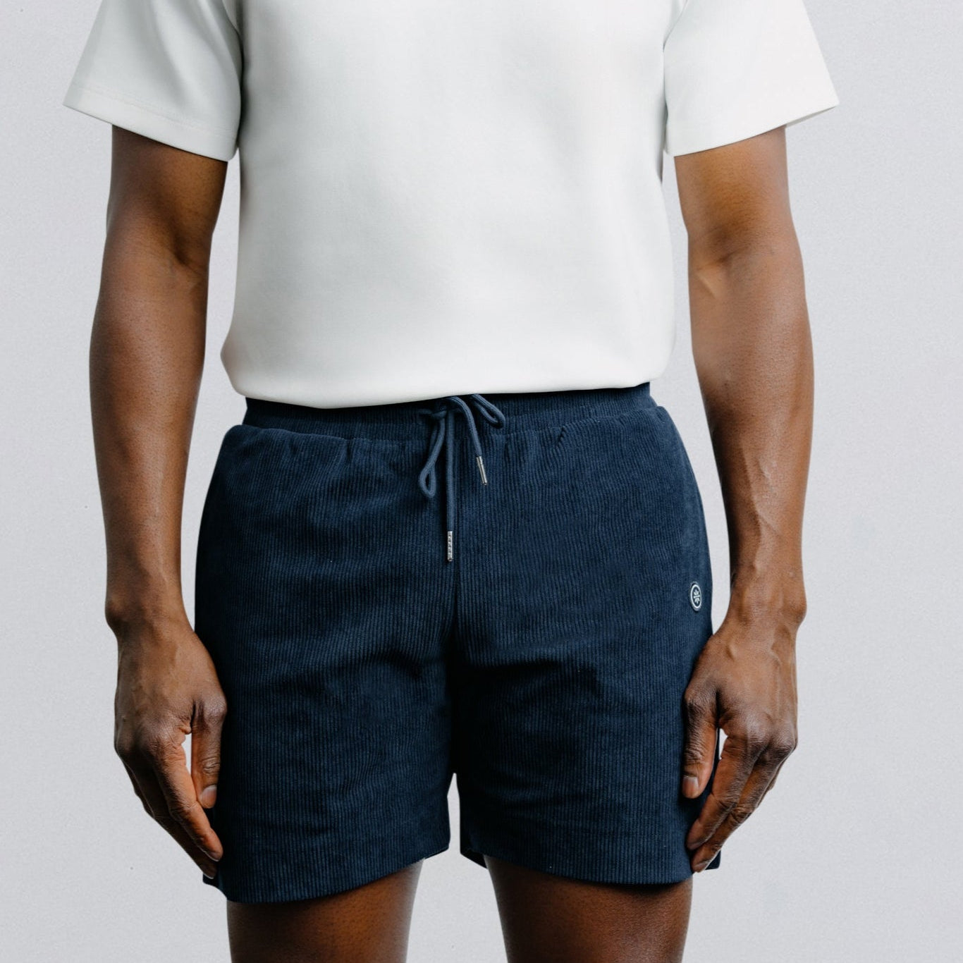 Person wearing a white t-shirt and navy shorts on a plain background