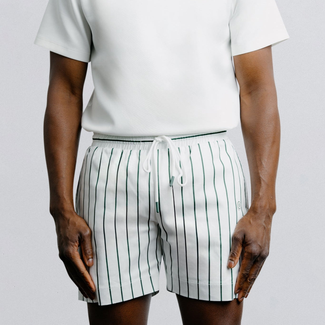 Person wearing a white t-shirt and striped shorts on a plain background