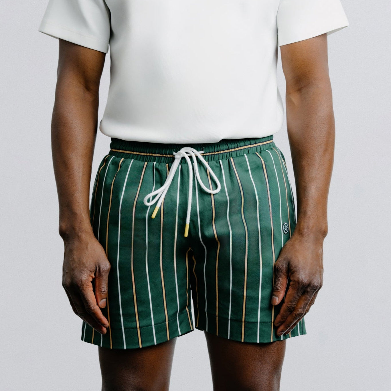 Person wearing green striped shorts and a white t-shirt on a plain background