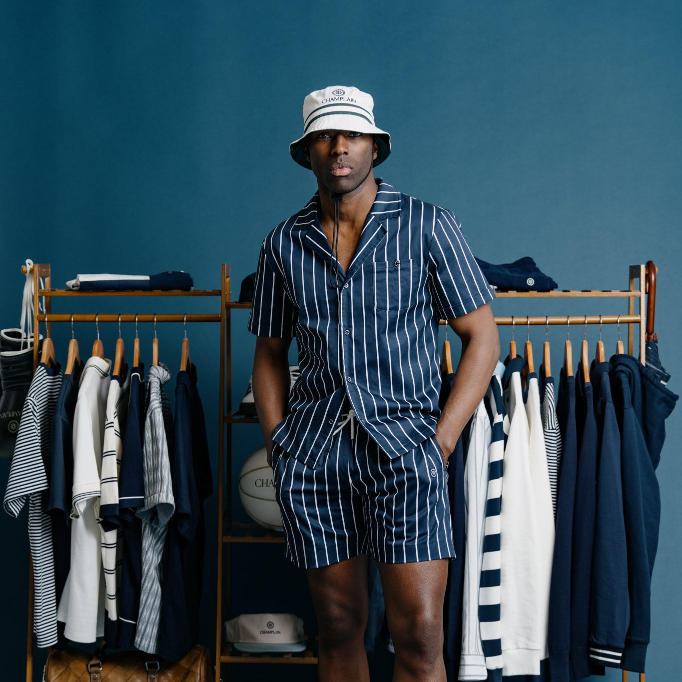 Person wearing a striped outfit standing in front of a clothing rack with various garments.