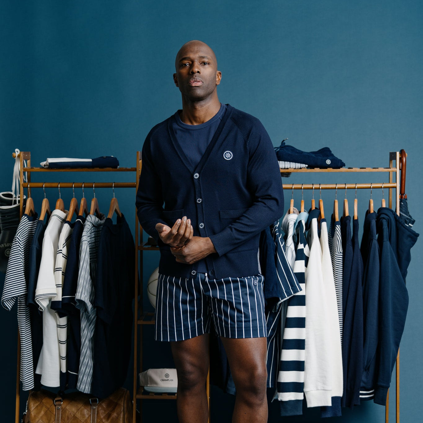 Man standing in front of a clothing rack with various garments on a blue background