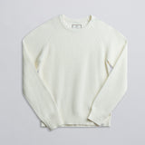 A long-sleeved cream-colored fisherman sweater displayed against a neutral background.