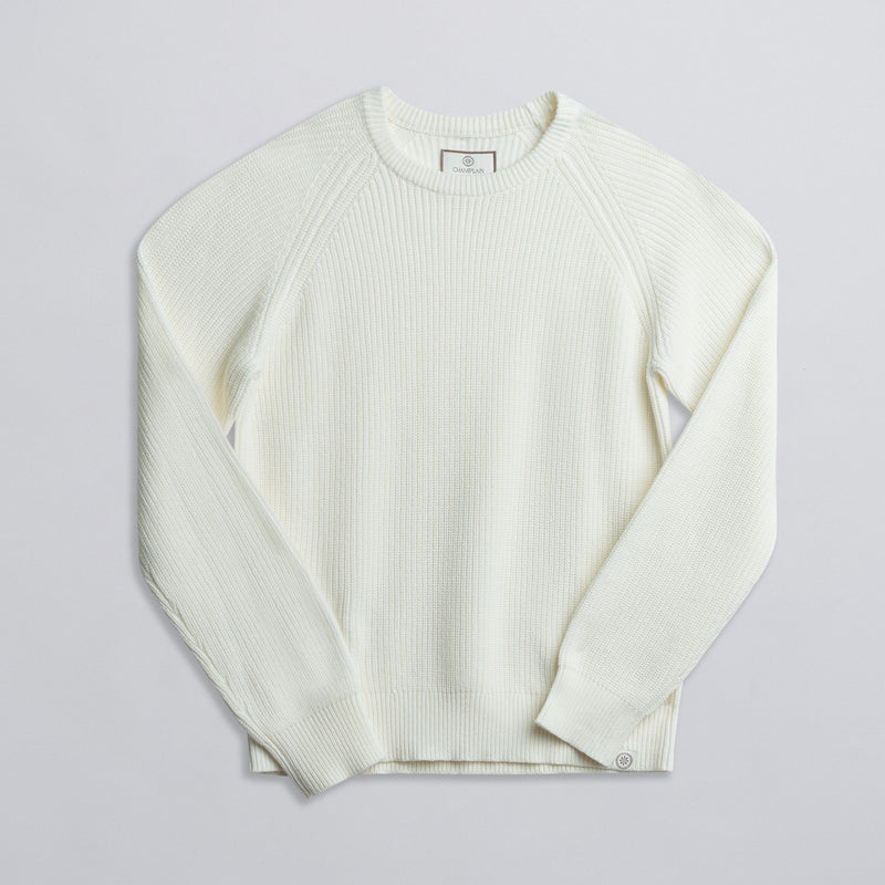 A long-sleeved cream-colored fisherman sweater displayed against a neutral background.