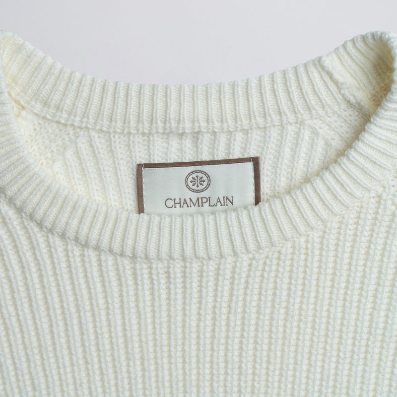 Close-up of a white sweater label on a plain background.