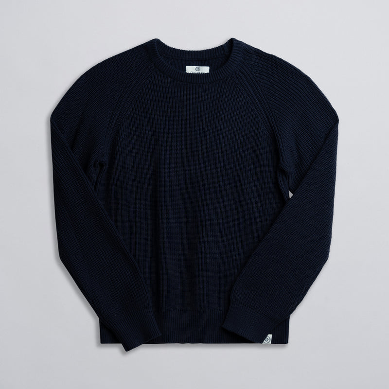 A navy-colored fisherman sweater displayed against a neutral background.