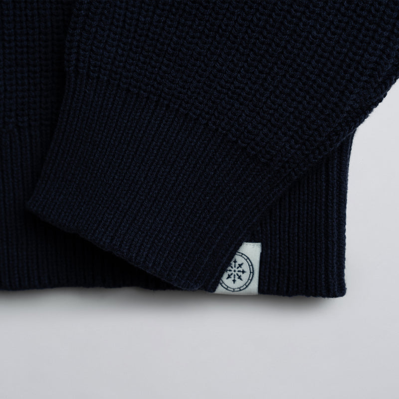 Close-up of a navy blue garment with a white label on a light gray background.