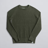 An olive green fisherman sweater laid out flat on a solid background.