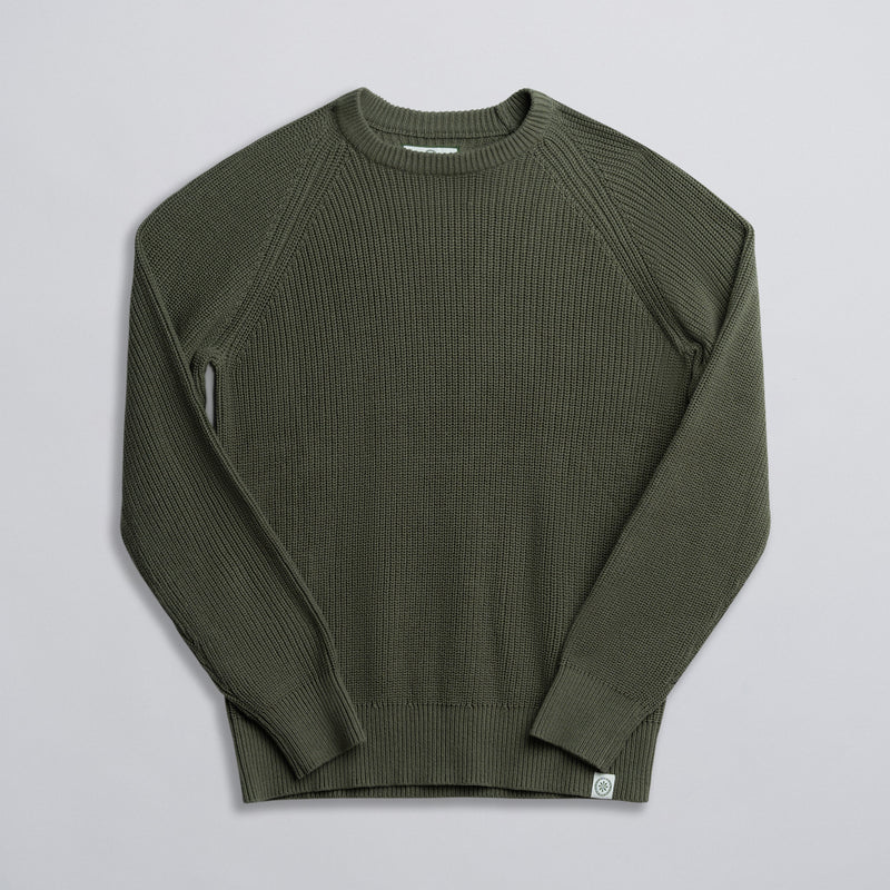 An olive green fisherman sweater laid out flat on a solid background.