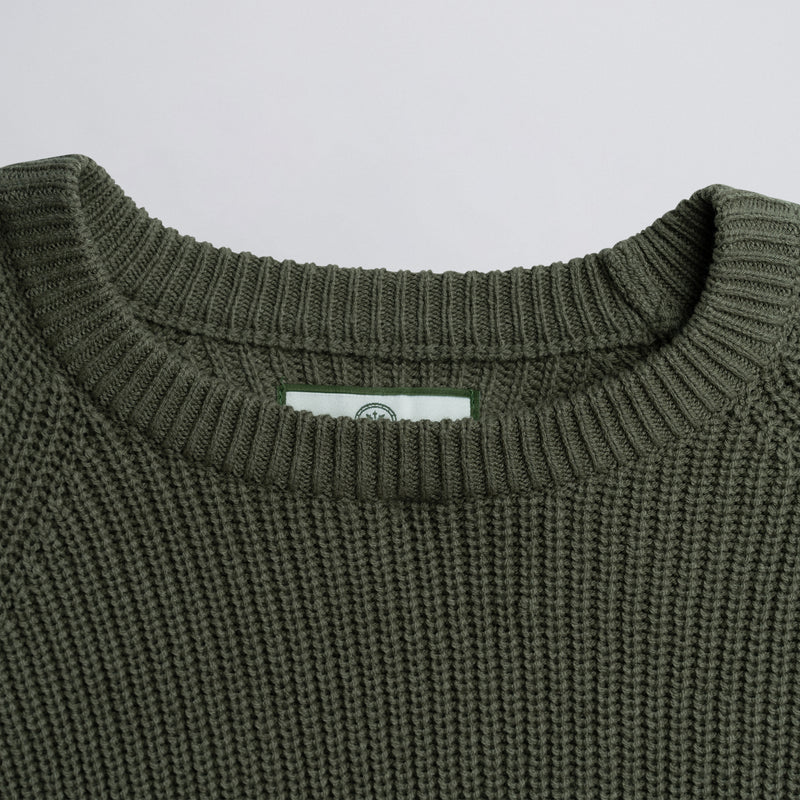Close-up of a green knitted sweater collar with a plain background.