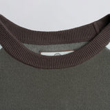 Close-up of the neckline of a brown sweater with a visible brand tag.