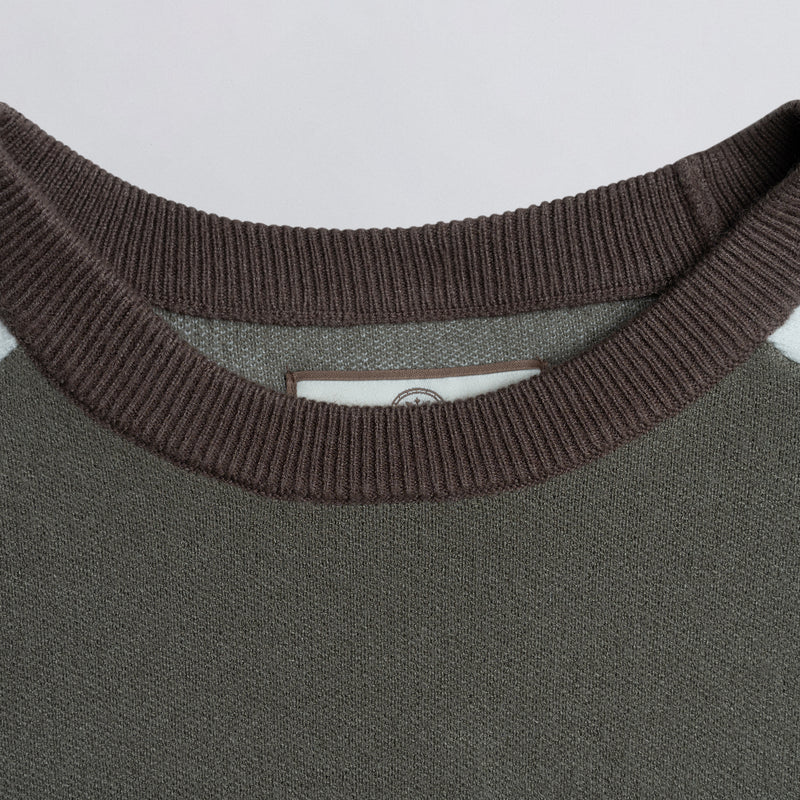 Close-up of the neckline of a brown sweater with a visible brand tag.