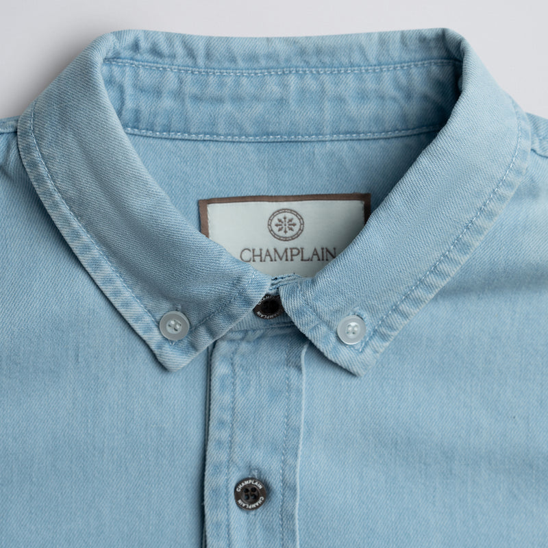 Close-up of light blue denim shirt collar and label.