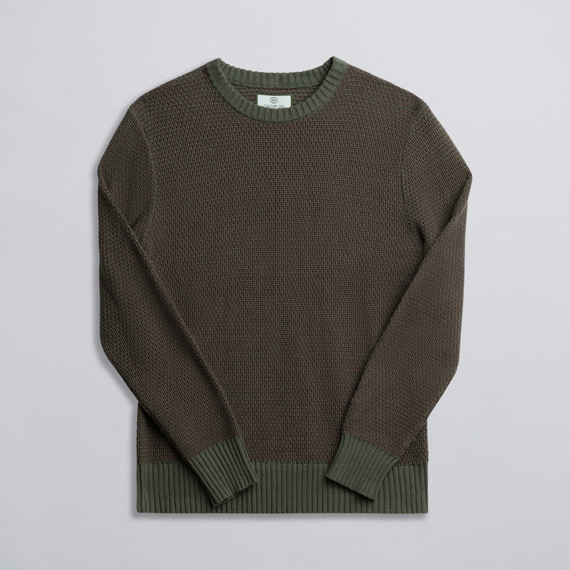 A green and brown two-tone knit sweater displayed against a neutral background