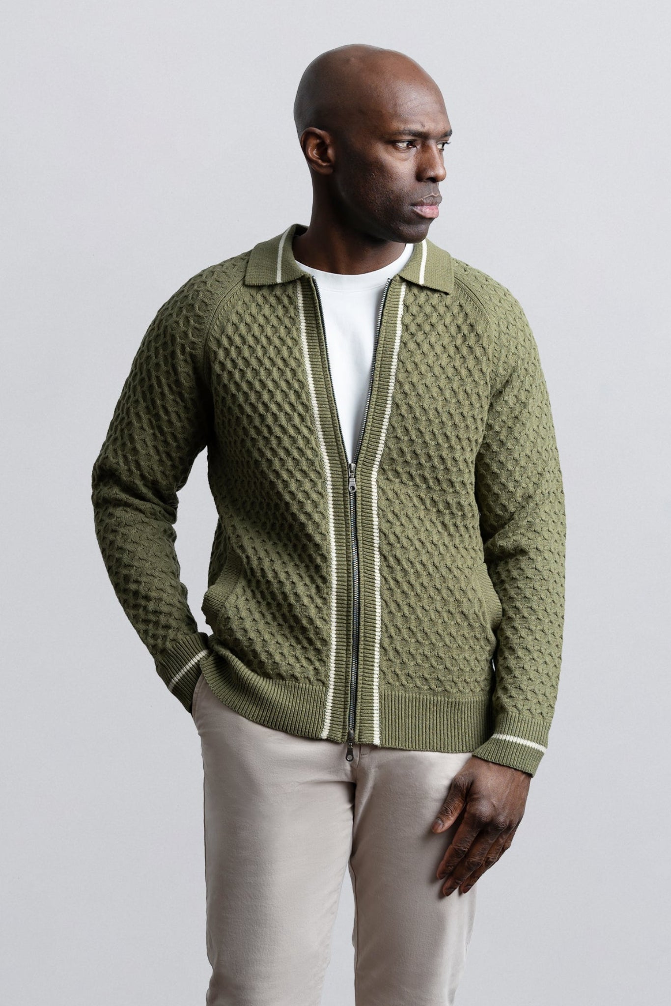 Man wearing a green textured sweater with a white background