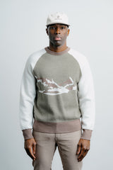 Man wearing a gray and white sweater with a graphic design on a plain background