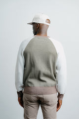 Man wearing a green and white sweater with beige pants on a plain background
