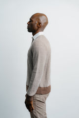 Man wearing a patterned sweater and beige pants against a white background