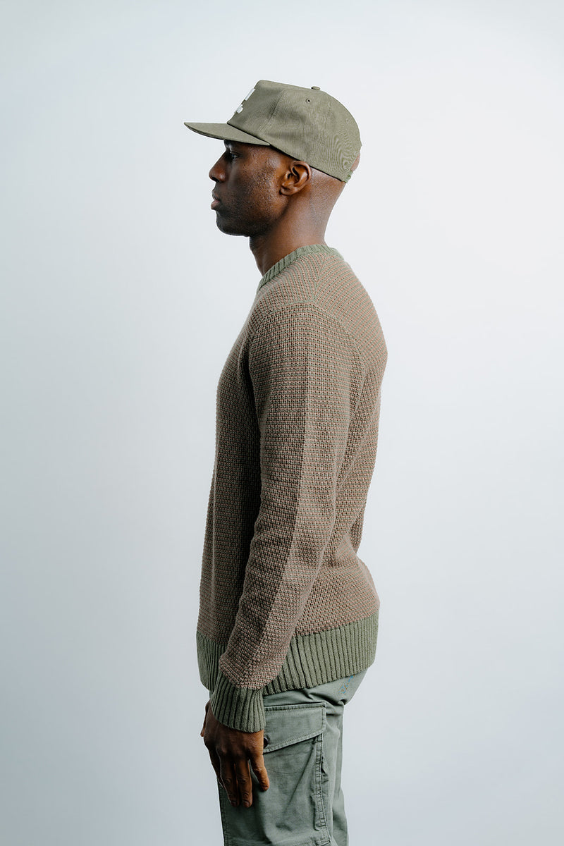 Man wearing a beige sweater and cap on a white background