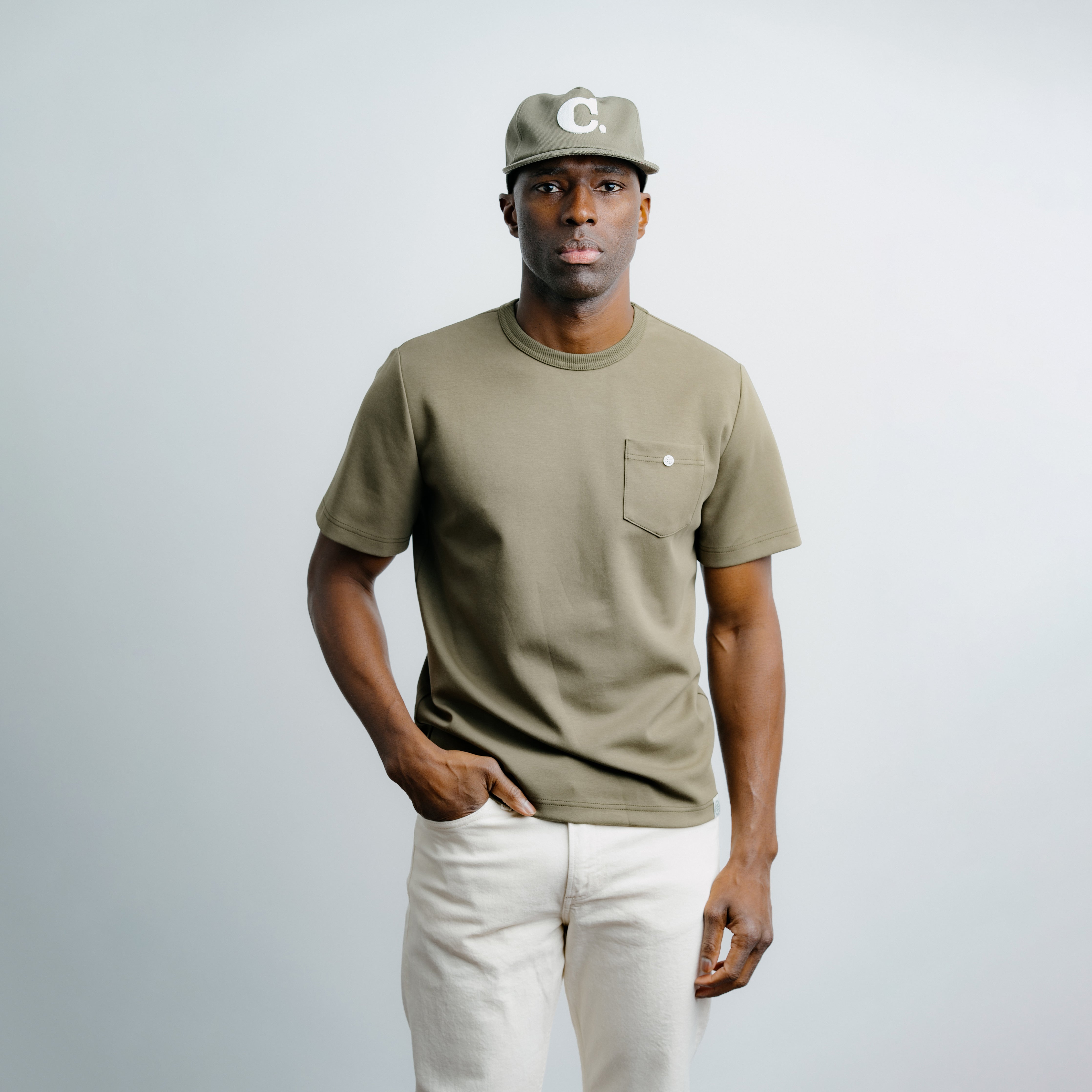 Man wearing a green t-shirt and cap on a plain background