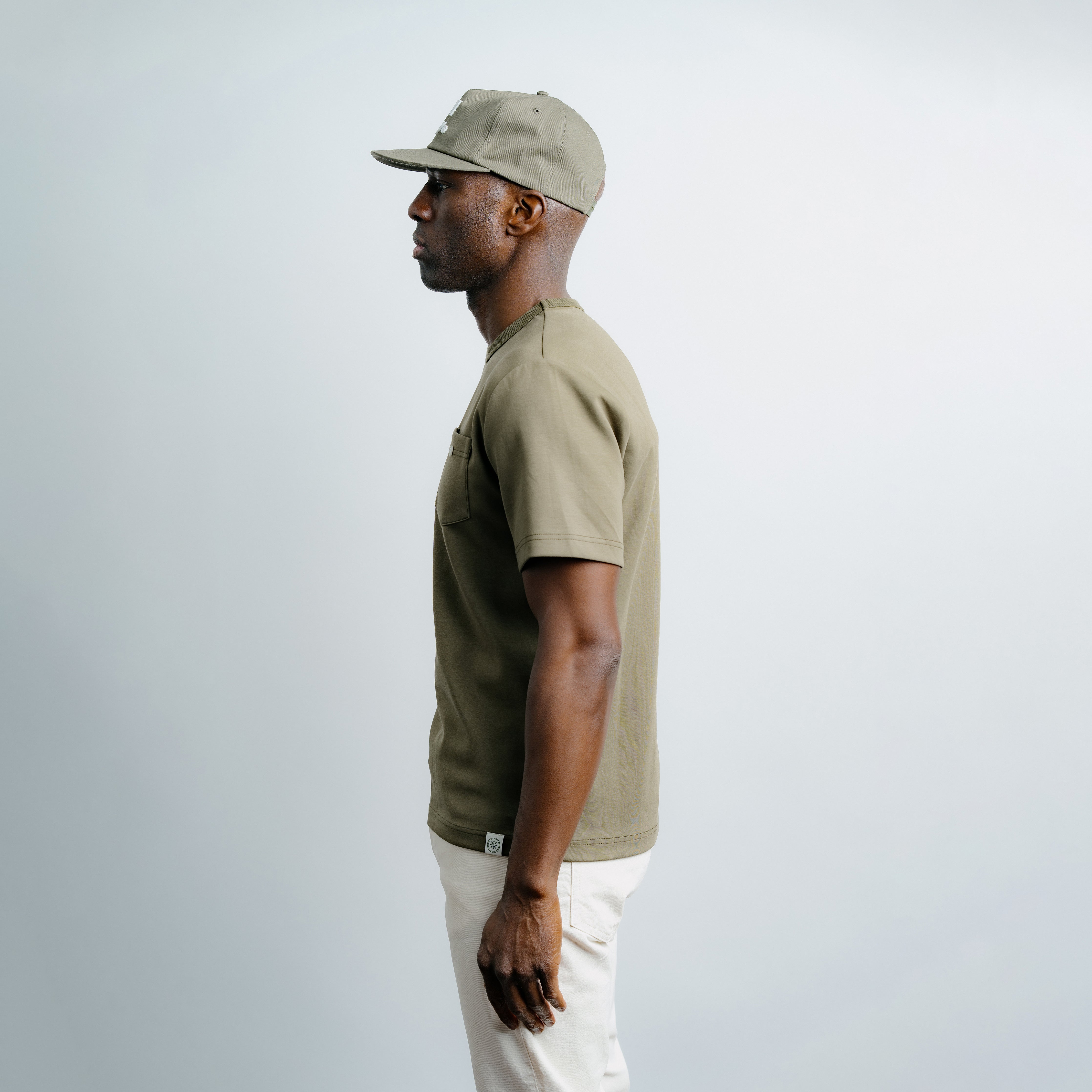 Man wearing a beige cap and green shirt against a white background