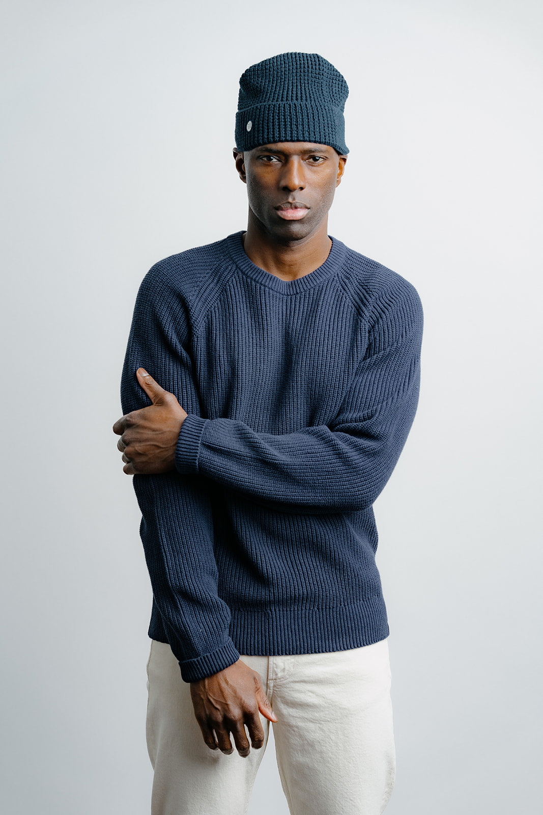 Man wearing a blue sweater and knit cap against a plain background