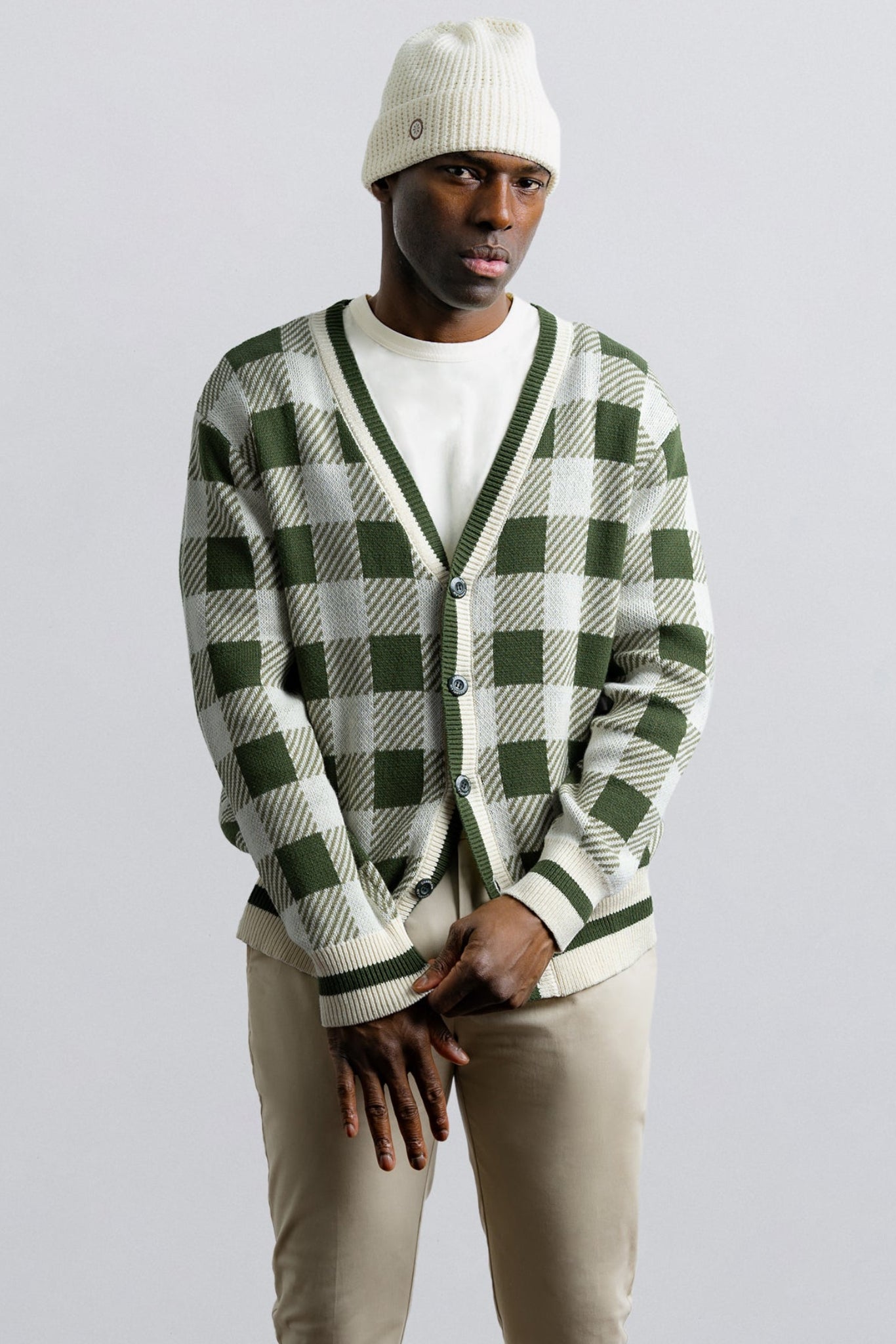 Person wearing a green and white checkered cardigan on a light gray background