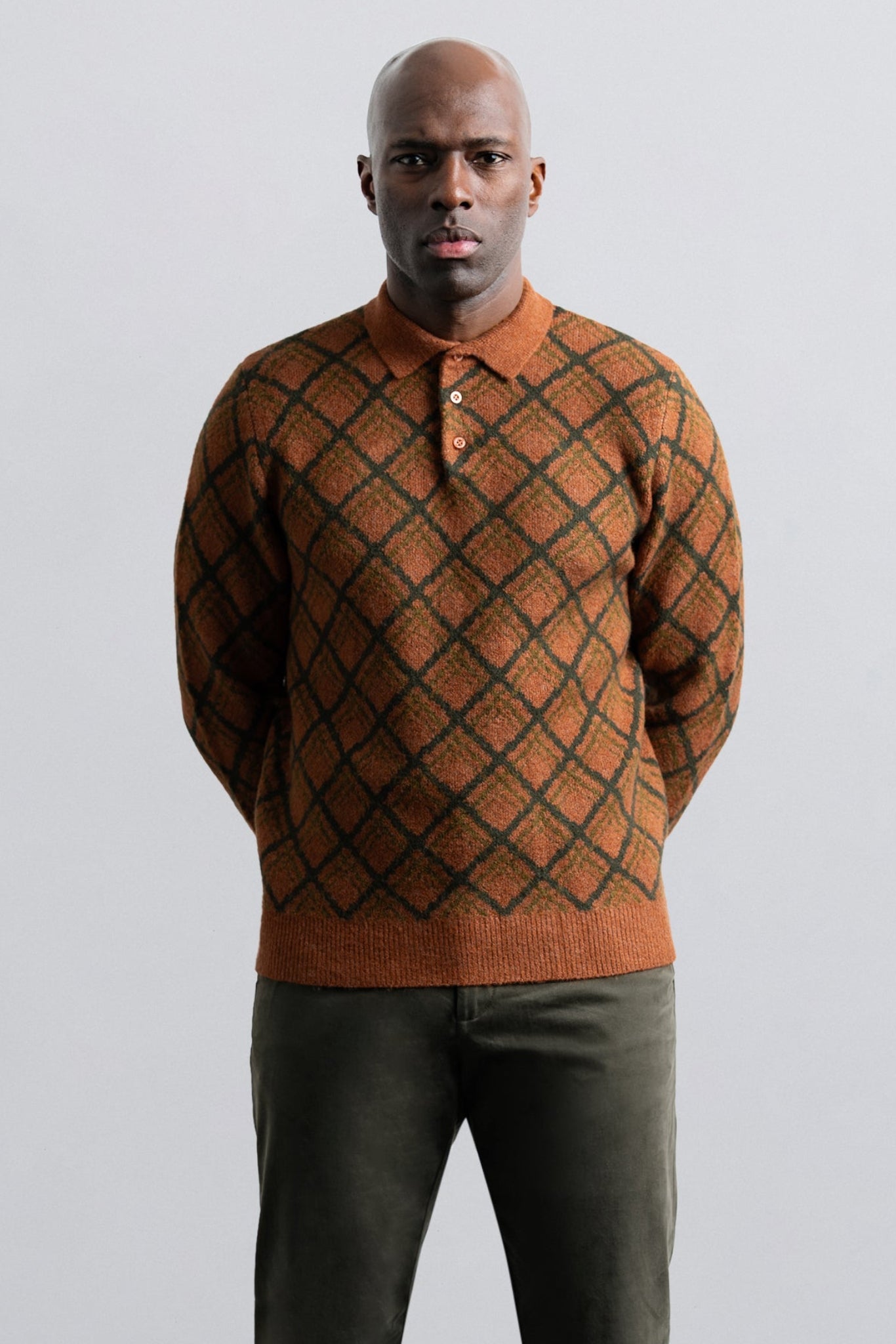 Man wearing a patterned brown sweater against a plain background