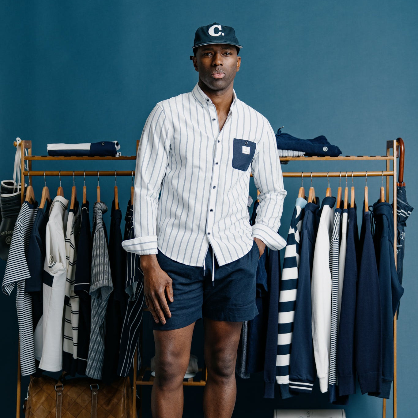 Man standing in front of a clothing rack with shirts on a blue background