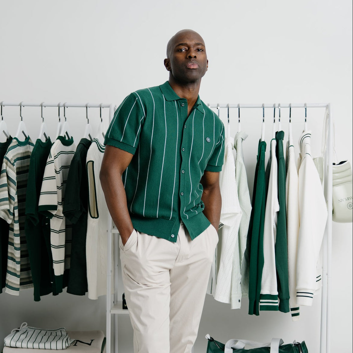Man standing in a room with clothing racks and green and white striped shirt