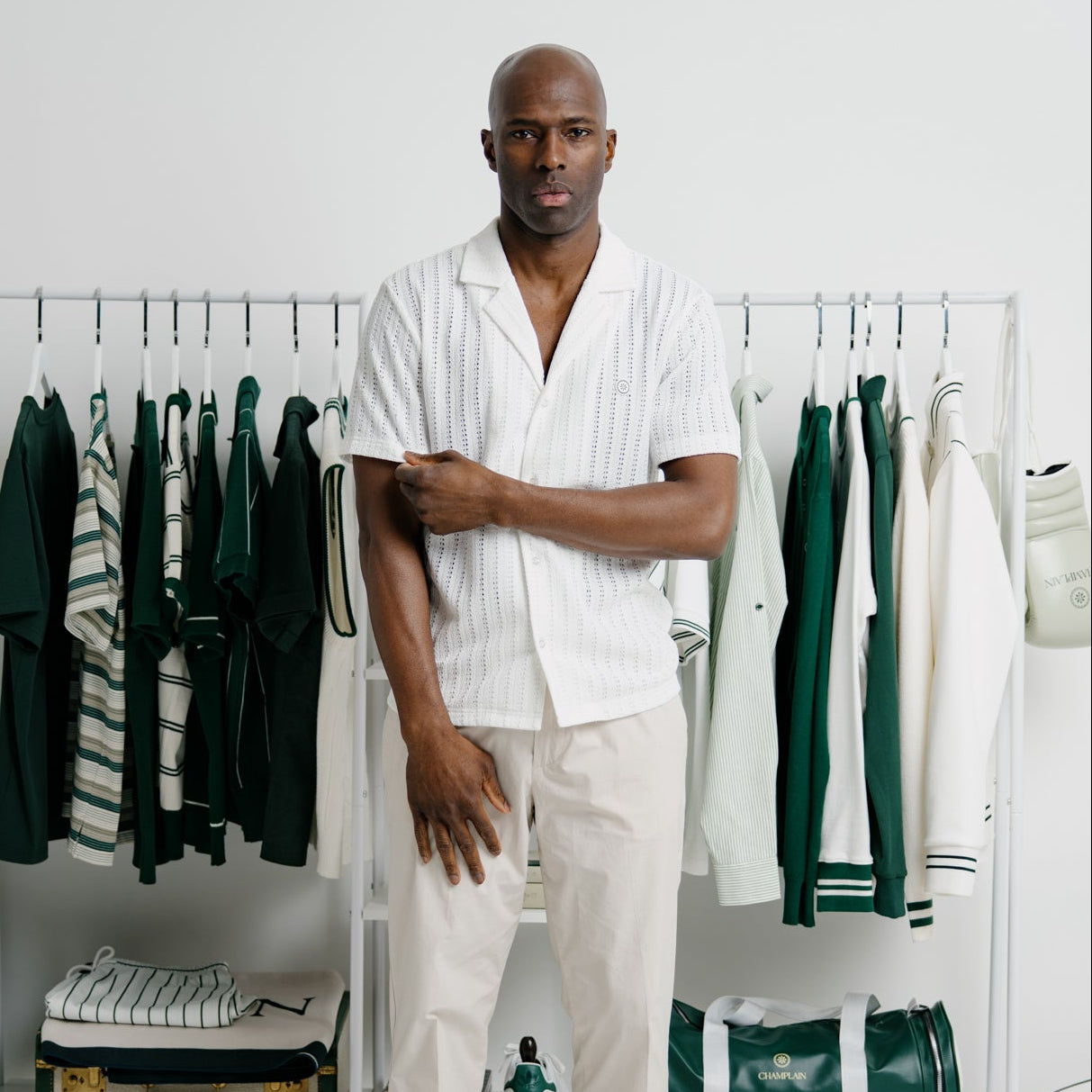Man standing in a room with clothing racks and green duffel bag
